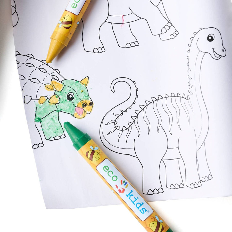 A closeup of a partly colored-in coloring page with dinosaur outlines with a yellow and a green eco kids crayon laying on top