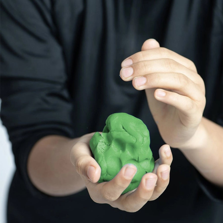 Picture of a child's hands holding a lump of green play dough. The background is the child's torso wearing a black shirt.