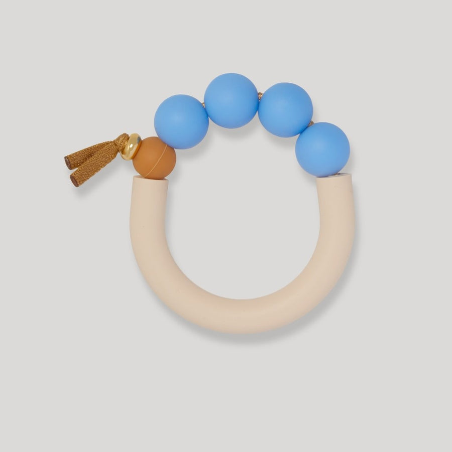 A picture of the January Moon Mayflower Arch Silicone Teething Bracelet on a gray background