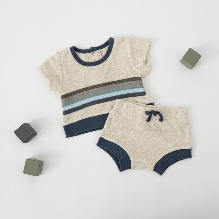 Picture of the tee and shorts laying on a white surface with several square wooden blocks in shades of gray
