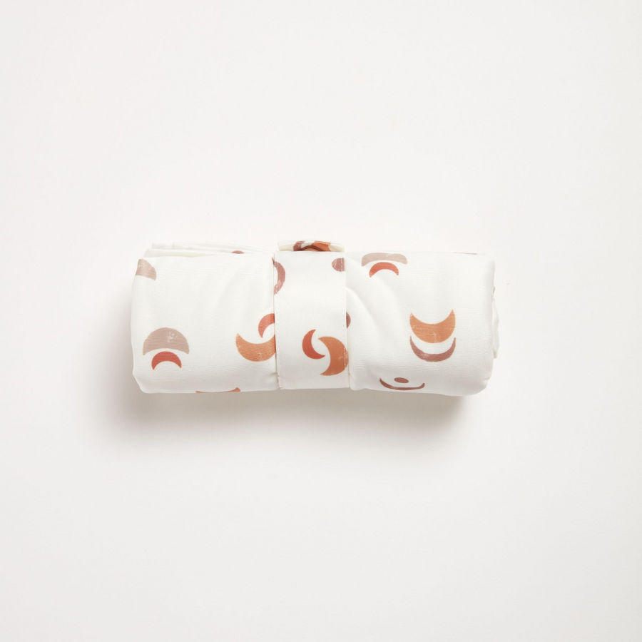 Rolled up changing mat, white with orange patterns on a light gray background