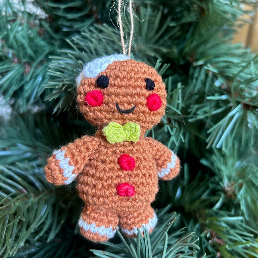 Crocheted gingerbread man ornament hanging on a Christmas tree.