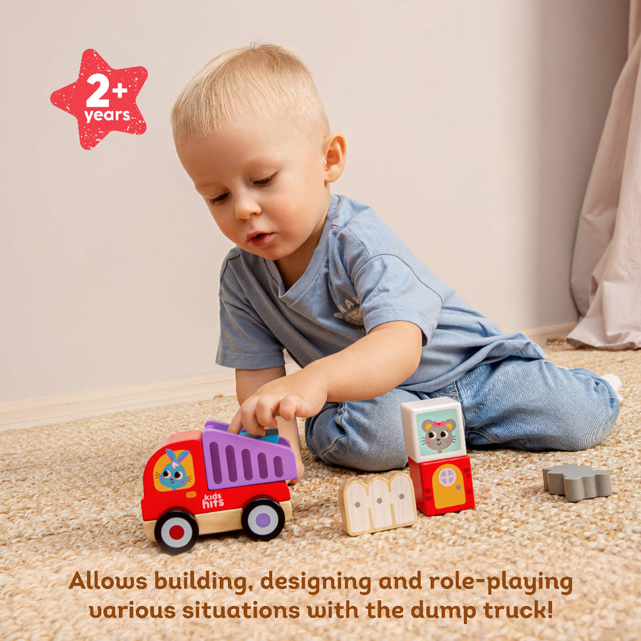 Child playing with a toy dump truck on a carpeted floor.