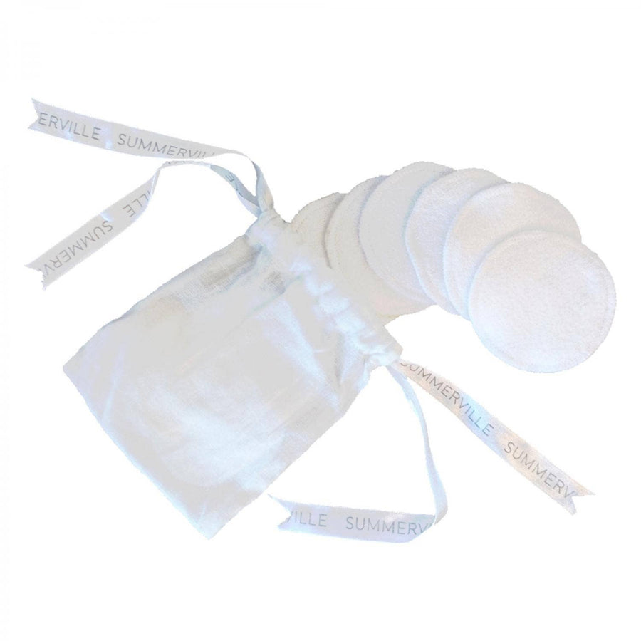 White cotton round pads with a white drawstring bag on a white background