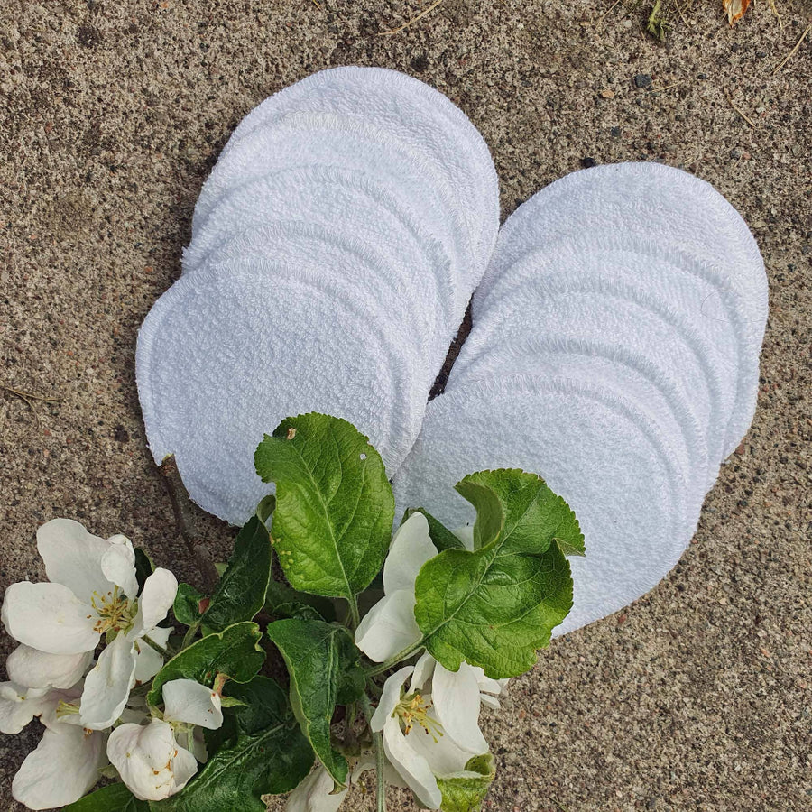 White circular towels with green leaves and white flowers on a brown surface