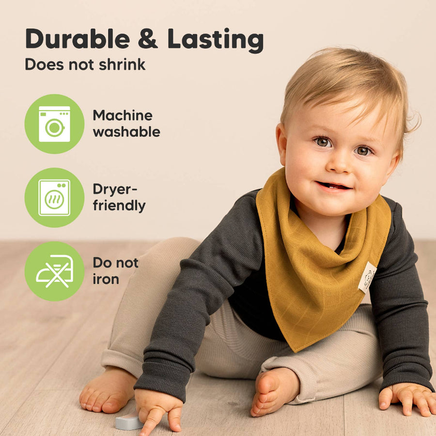 Baby wearing a mustard yellow bib with text about product durability and care on a beige background