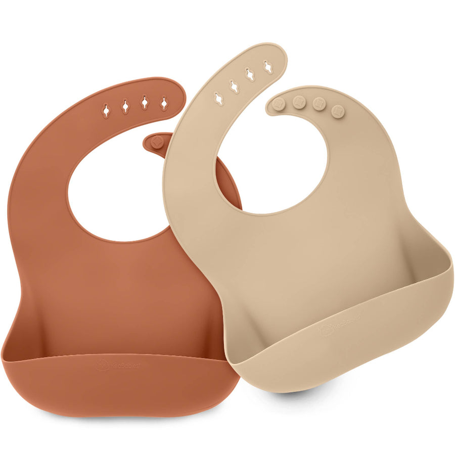 Two silicone baby bibs, one brown and one beige, on a white background.
