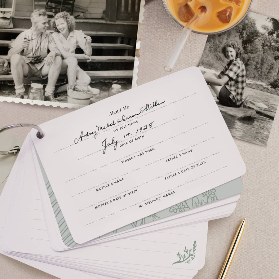 picture of the journal open to the about me page, on a gray surface with a gold pen and two black and white photos of people from the 1940s and a glass of iced tea or coffee. The name and date of birth are filled out, reading 