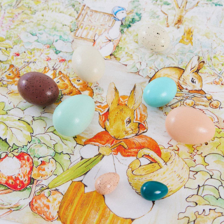 several painted eggs on a fabric printed with strawberry plants and rabbits