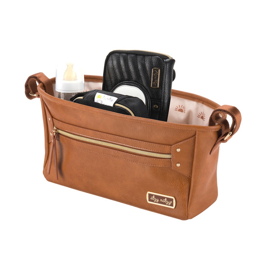 Brown leather bag with gold zipper and handles, containing a black wallet and other items on a white background.