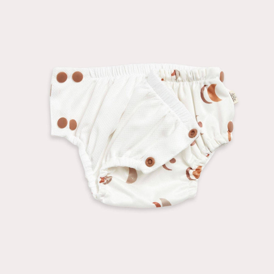 White swim diapers with brown snaps on a light pink background