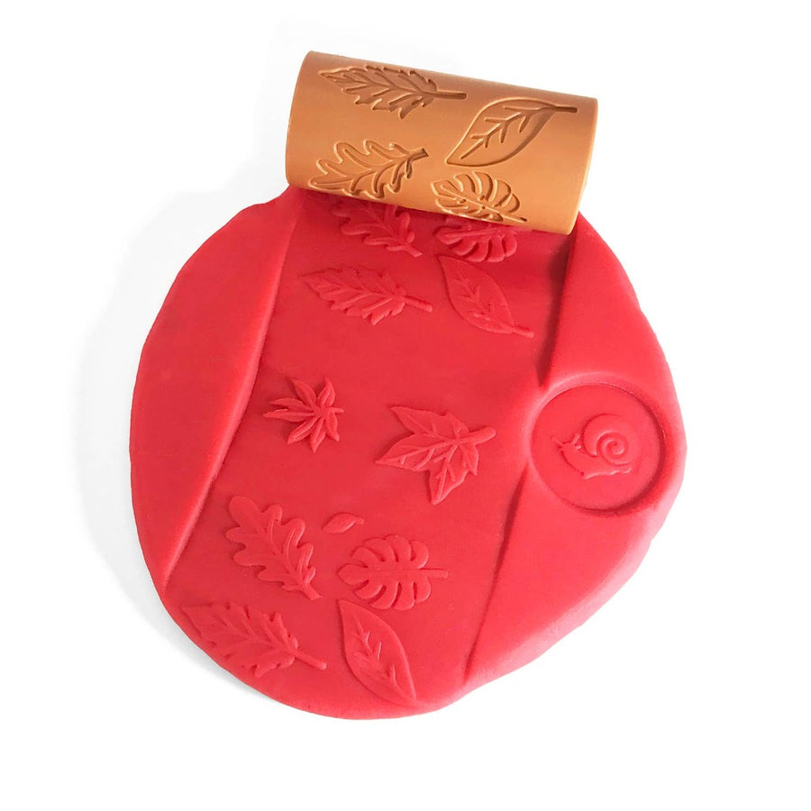 Picture of some red play dough that has been stamped with a snail impression, with the Garden roller that has been rolled across it creating leaf impressions