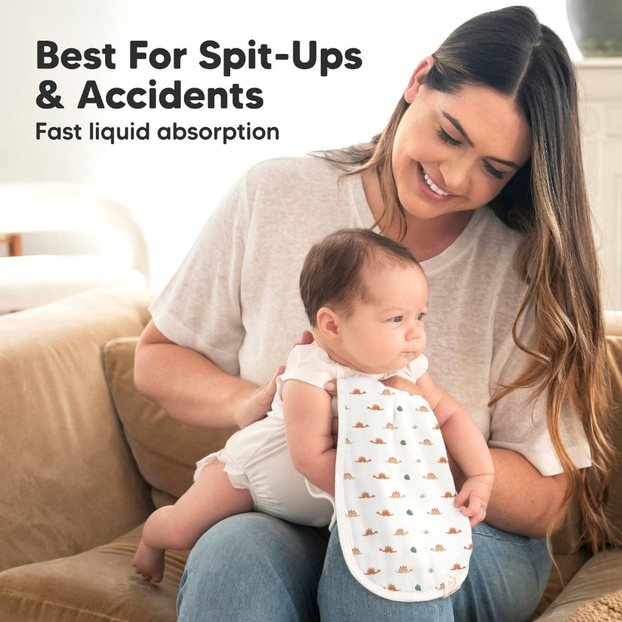 Woman holding a baby wearing a bib with text about spit-ups and accidents.