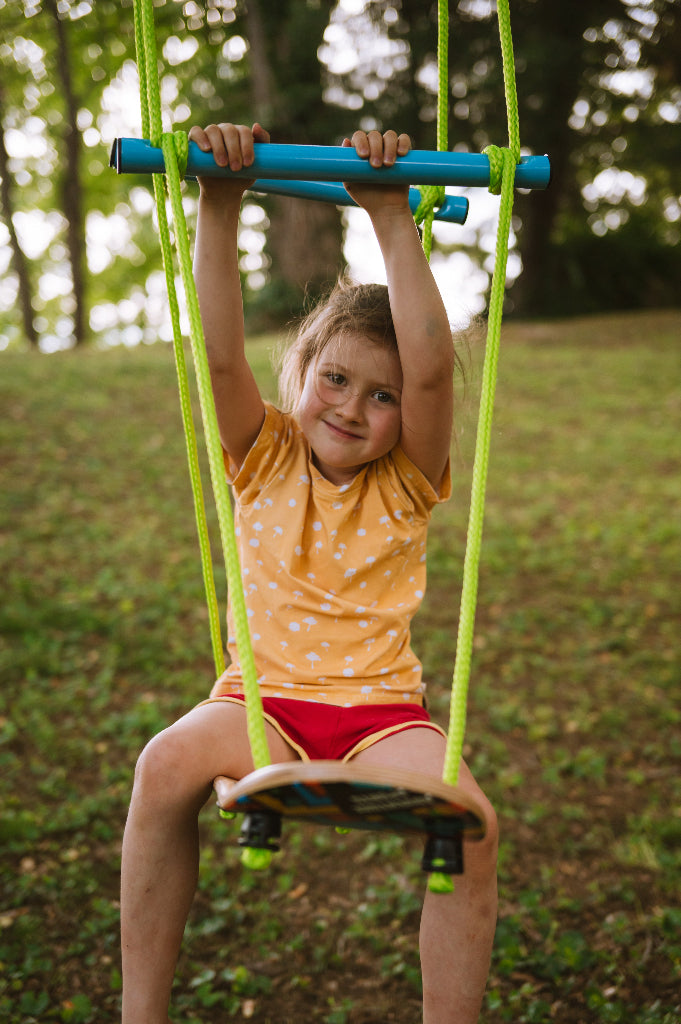 Child on a swing in a park with trees in the background