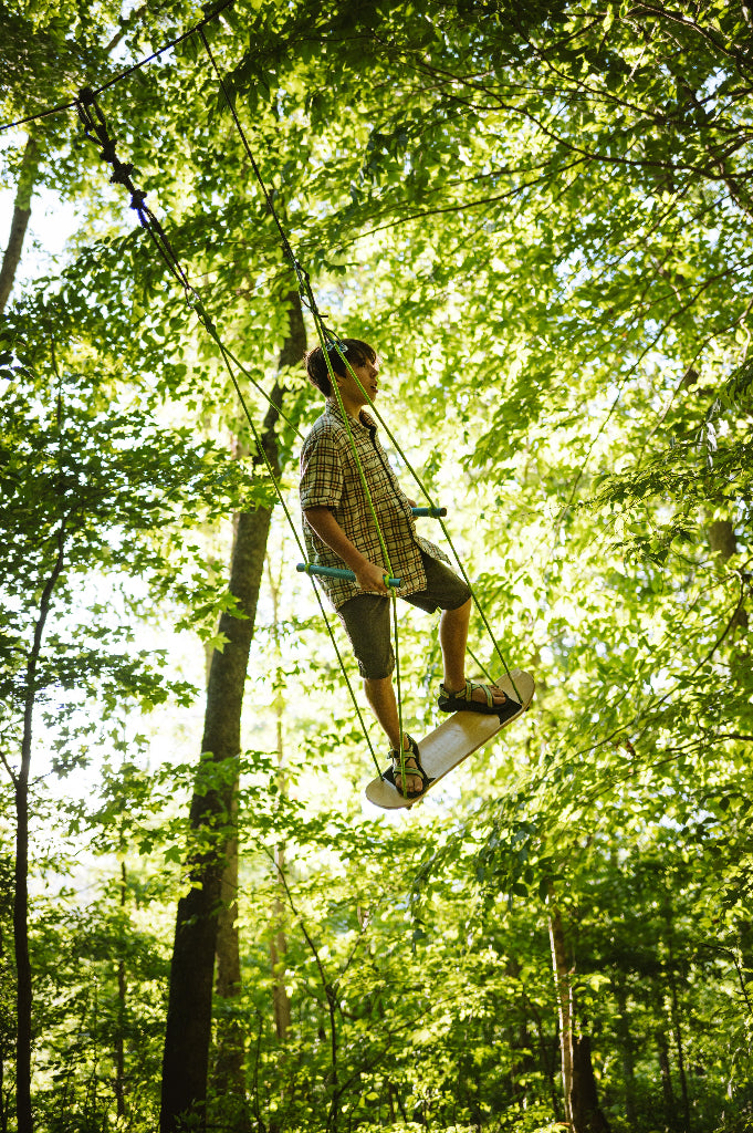 Person on a swing high in the trees with green foliage