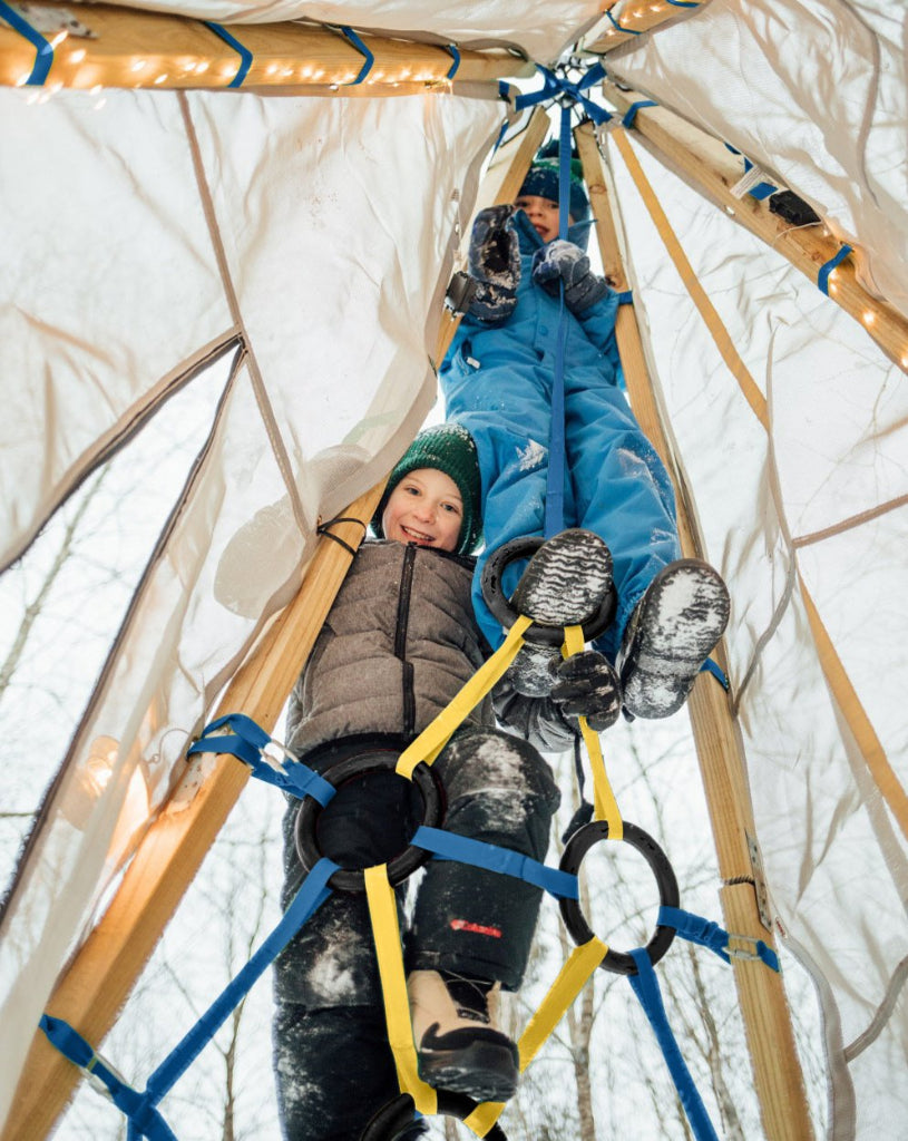Two children playing inside a dome-shaped structure with wooden beams and ropes.