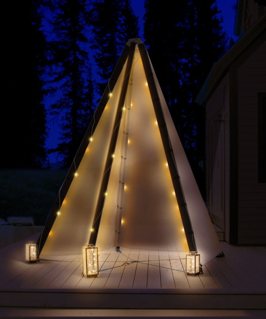Triangular outdoor structure with string lights and lanterns on a wooden deck at night.