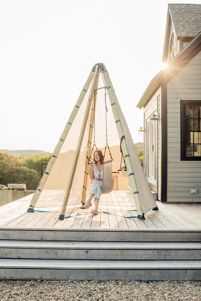 Woman sitting on a swing on a wooden deck with a house in the background