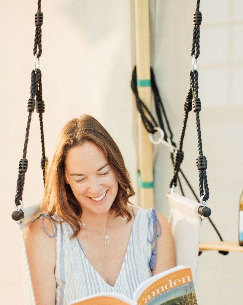 Woman reading a book on a swing with a blurred background