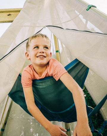 Child playing inside a green and white play tent