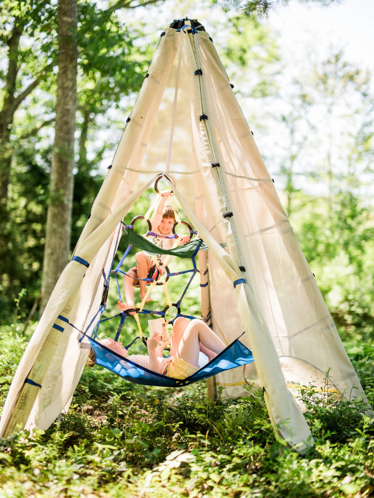 Children playing in a hammock attached to a teepee in a forest setting