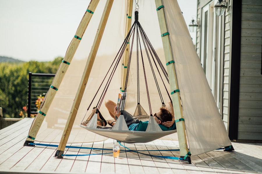 Person relaxing in a hammock on a wooden deck with a scenic background