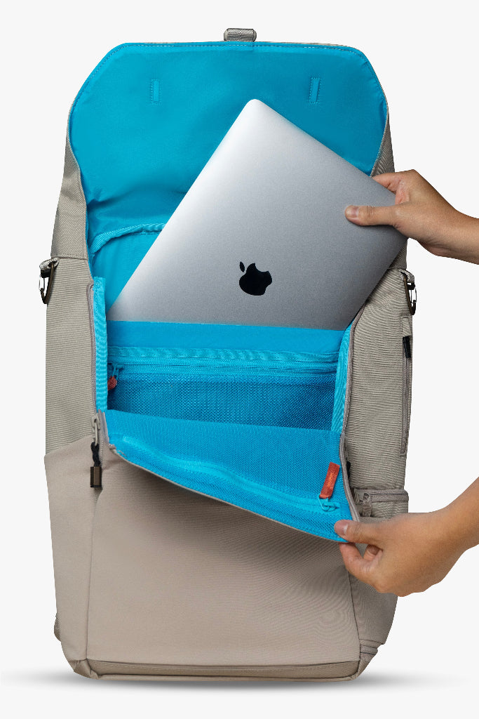 Backpack with blue interior compartment holding a laptop, being held by a person.