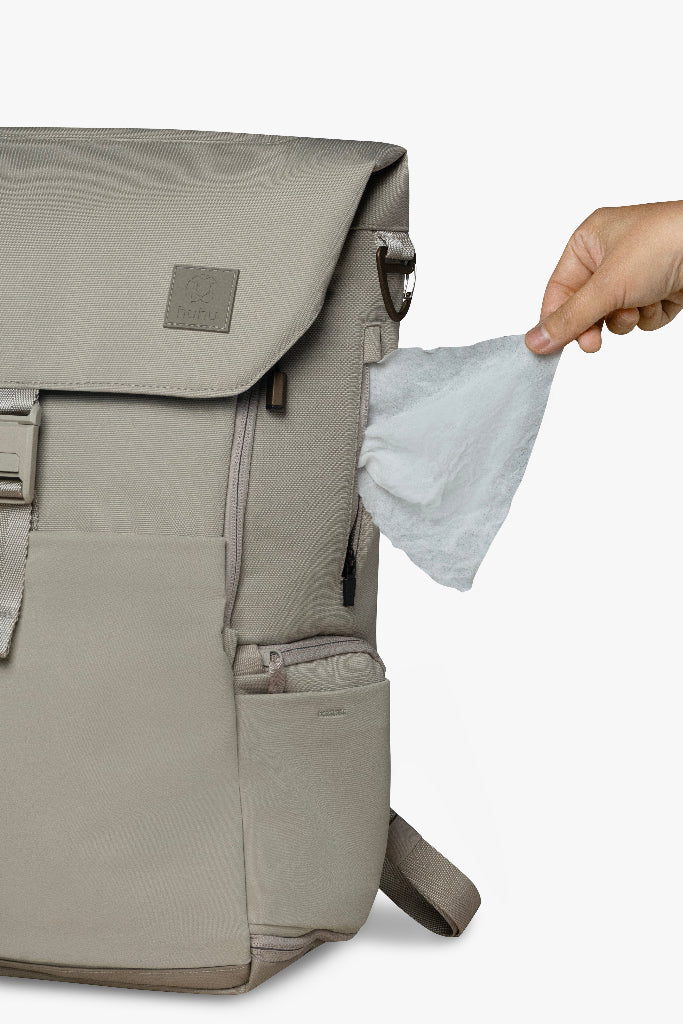 Beige backpack with a handpulling a wipe from a wipes pocket, on a white background