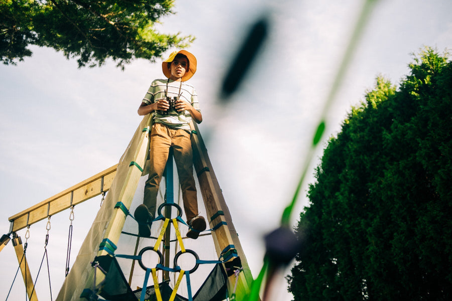 Person sitting on a playground structure with trees in the background