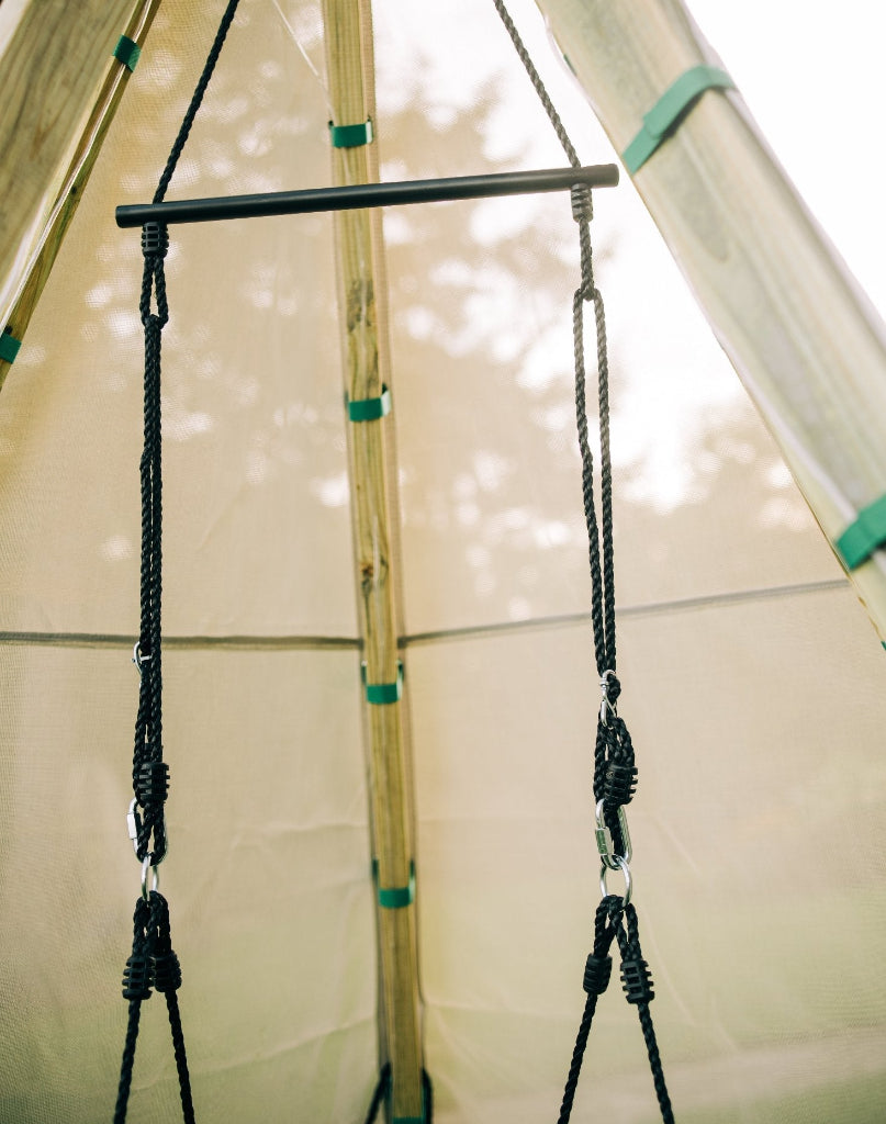 Swing hanging from a teepee structure with ropes and wooden support beams.