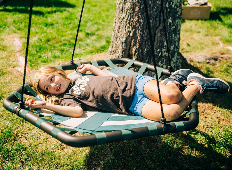 Child lying on a green swing set in a park