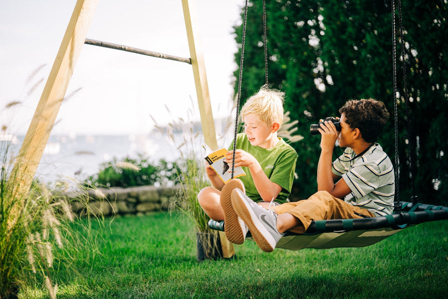 Two children on a swing set in a garden