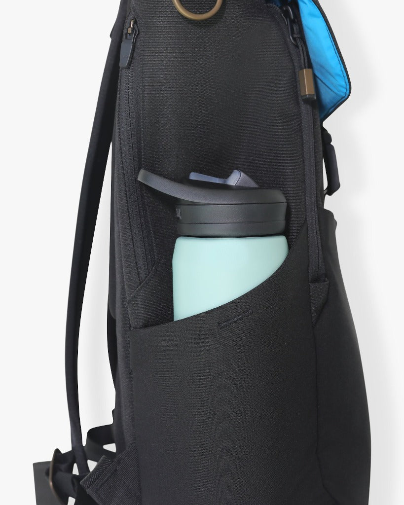 Picture of a side view of the backpack against a white background with a mint-colored water bottle with a black plastic top in the side bottle pocket