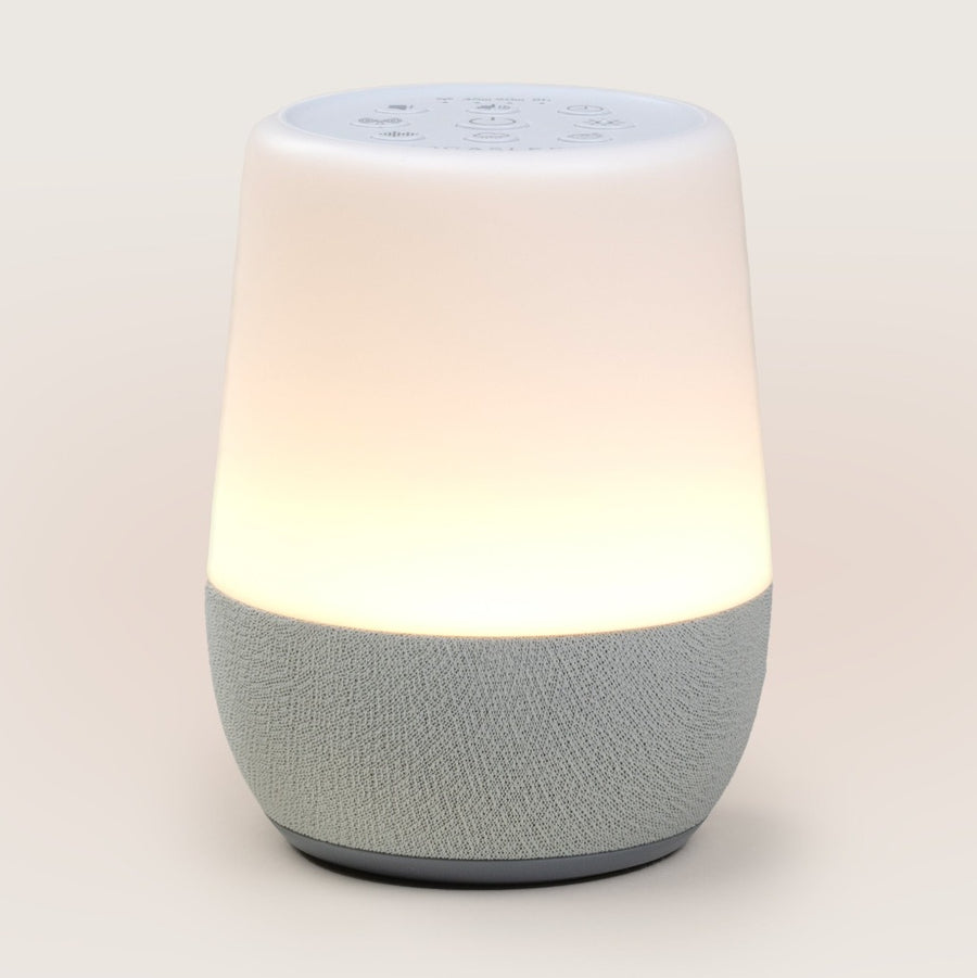 Picture of the white noise machine with the light on, against a light colored background