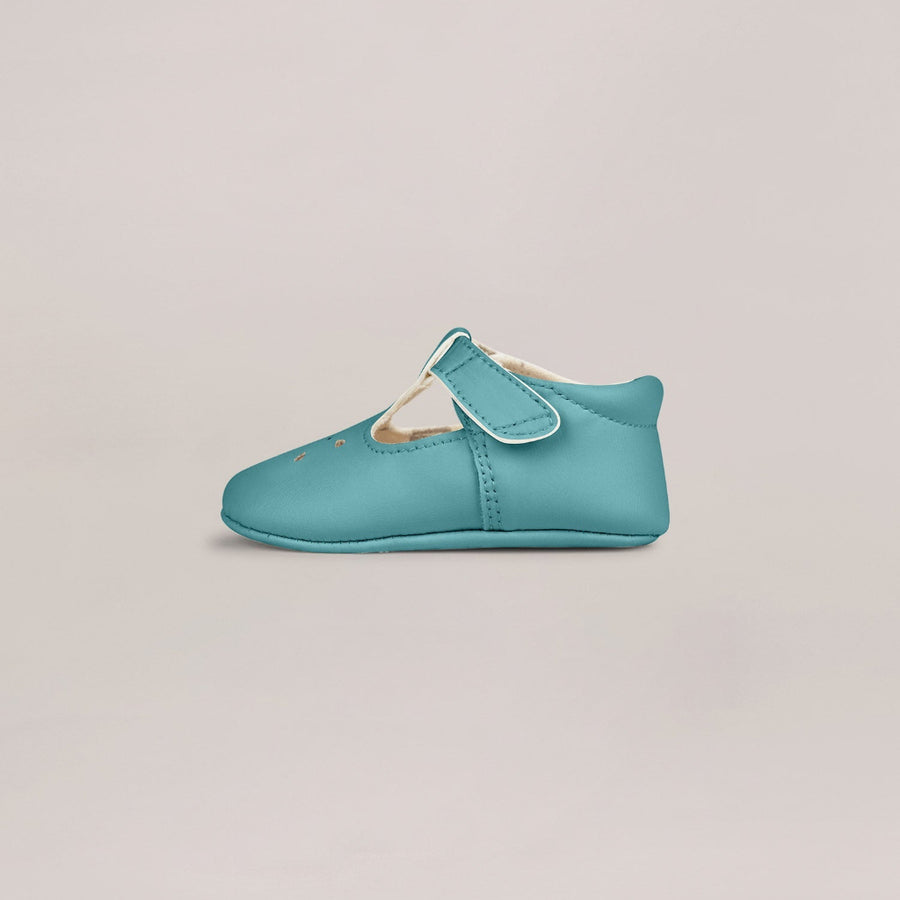 Turquoise baby shoe on a light gray background