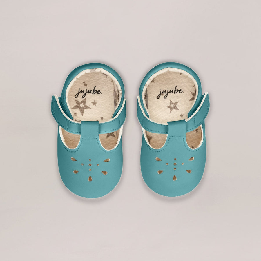 Pair of turquoise baby shoes with 'joyube' branding on a light gray background