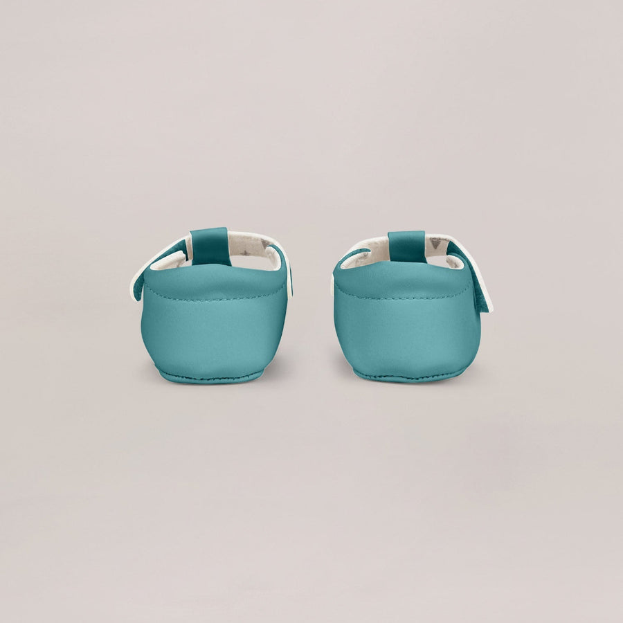 Pair of teal baby shoes on a light gray background