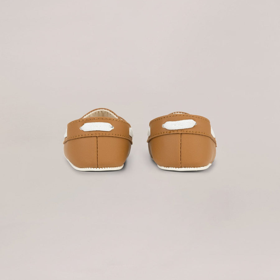 Pair of brown baby shoes on a beige background