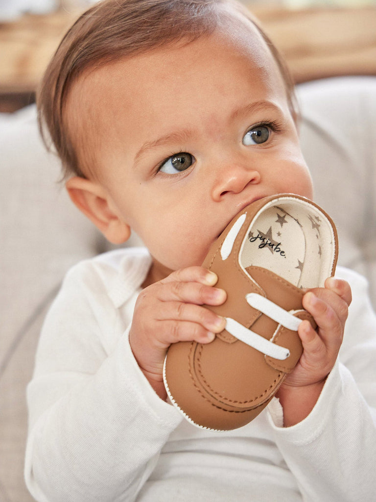 Baby holding a brown shoe with white laces