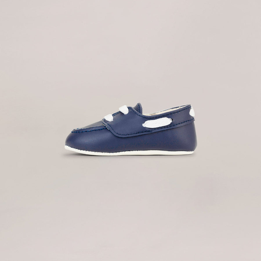 Navy blue baby shoes with white sole on a light gray background