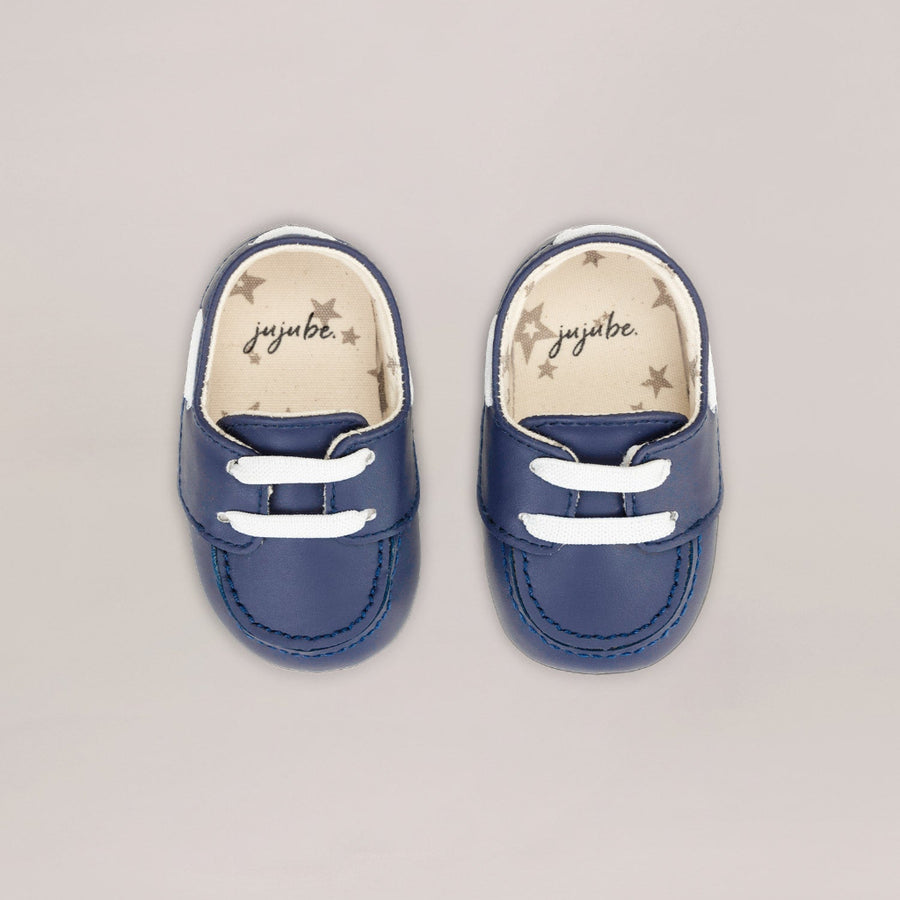 Pair of blue baby shoes with white laces on a light gray background