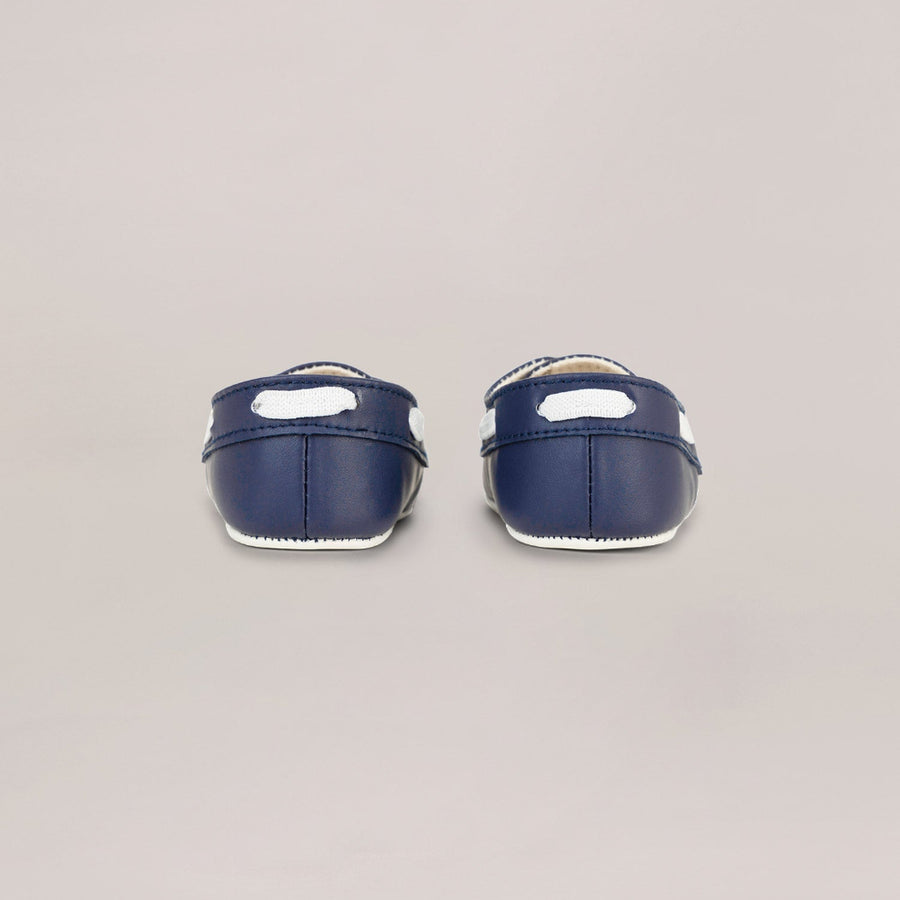 Pair of navy blue baby shoes on a light gray background