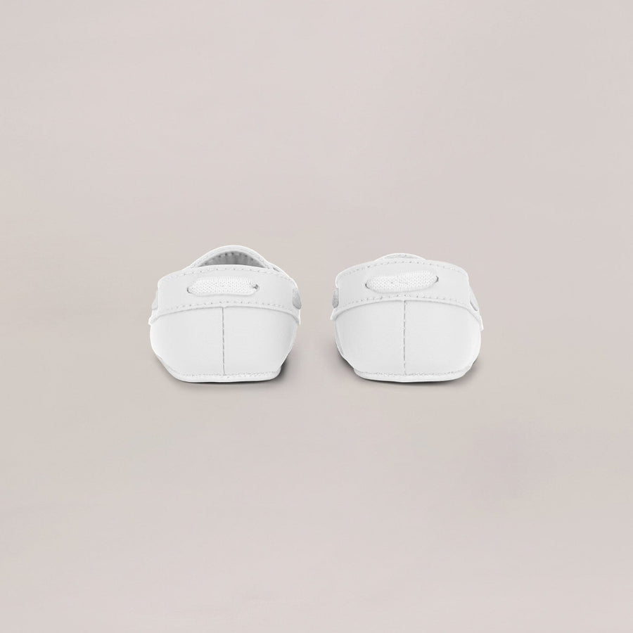 Pair of white baby shoes on a light gray background