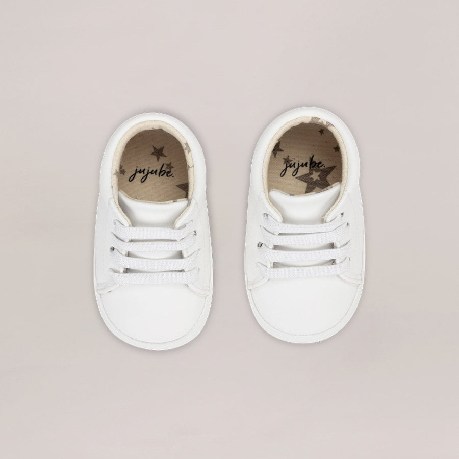 Pair of white sneakers with 'juju' branding on a beige background