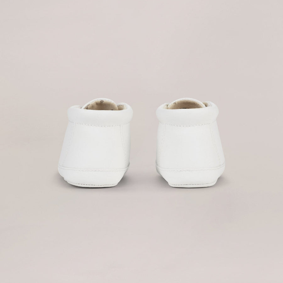 Two white high top sneakers on a light pink background