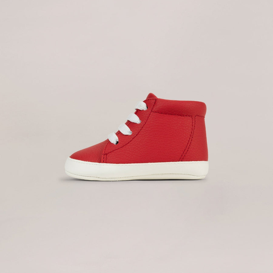 Red high-top sneaker with white sole on a light pink background