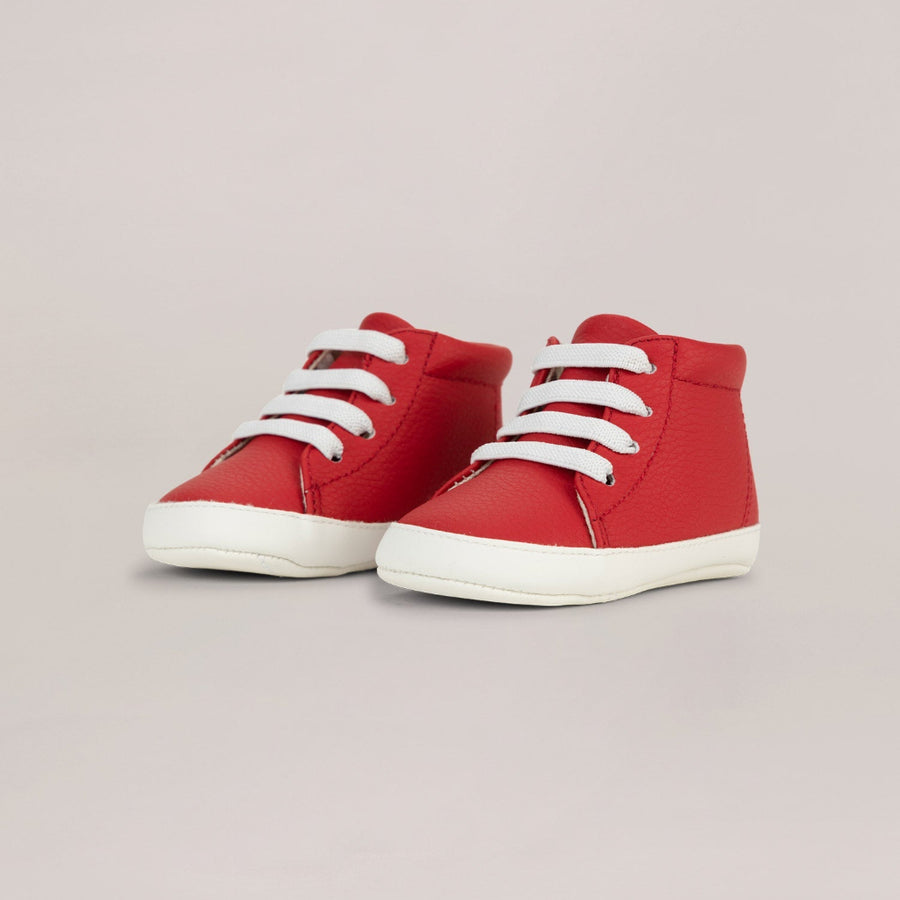 Red high-top sneakers with white laces on a light gray background