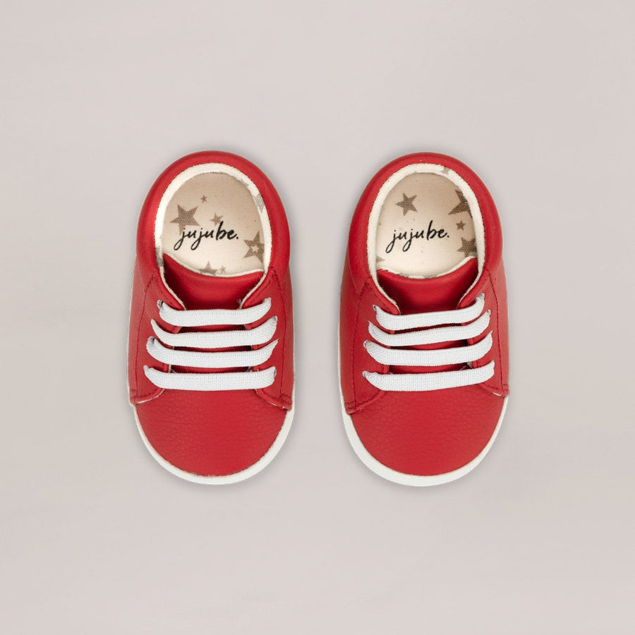 Red high-top sneakers with white stripes on a light gray background