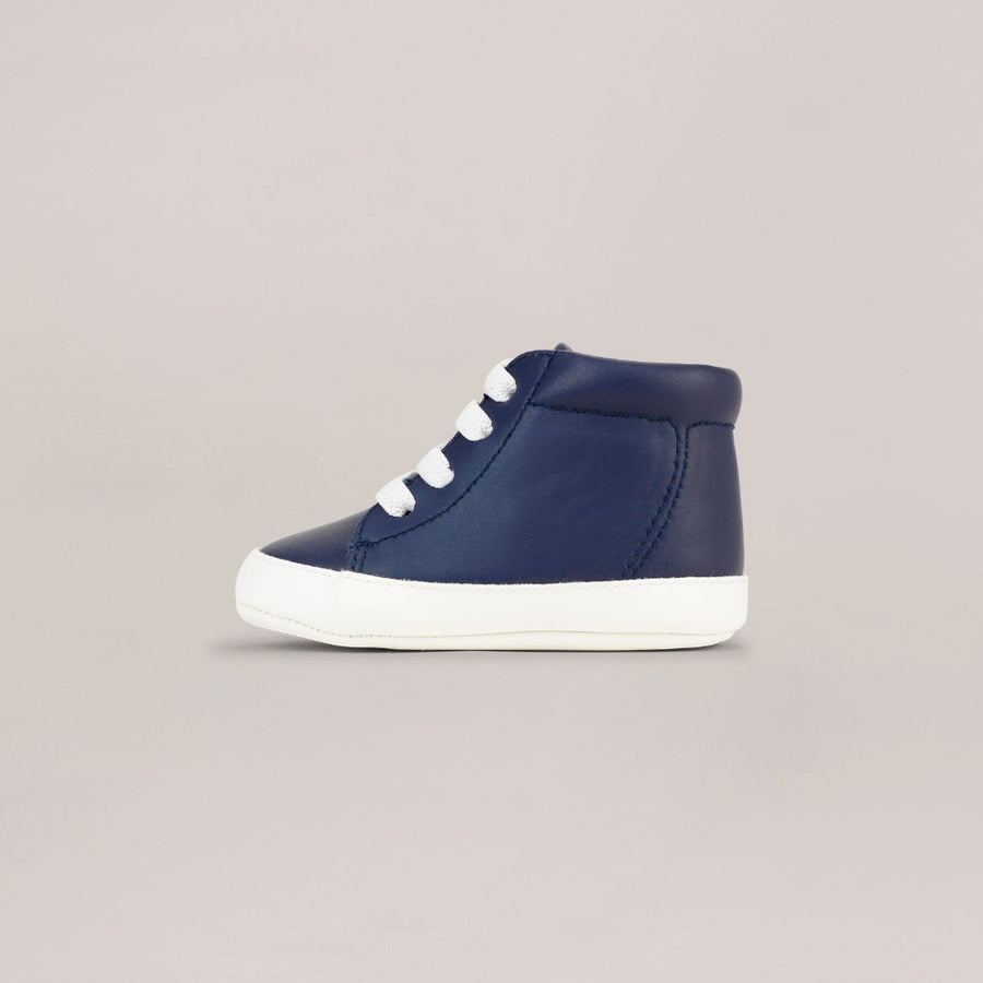 Navy high-top sneaker with white laces on a beige background