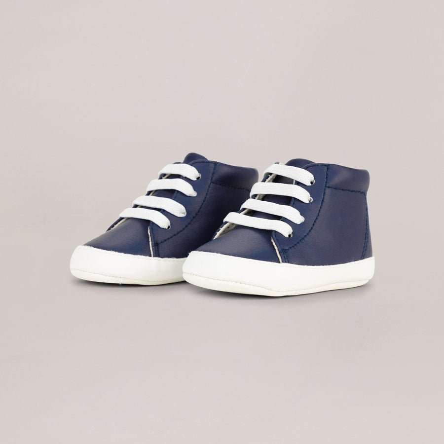 Pair of navy high-top sneakers with white laces on a light gray background